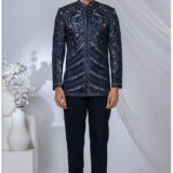Man wearing a midnight blue Jodhpuri suit with intricate peacock and floral embroidery, styled with a mandarin collar.