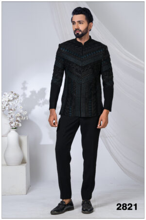 Man wearing a black Jodhpuri suit with intricate geometric embroidery in blue and black tones.