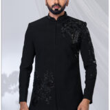 Man wearing a black Jodhpuri suit with intricate eagle motif embroidery on the chest and sleeve.