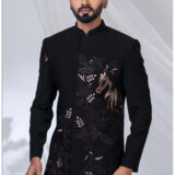 Man wearing a black Jodhpuri suit with embroidered horse and floral motifs in bronze shades.