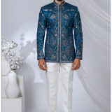 Man wearing a royal blue Jodhpuri suit with heavy floral and paisley embroidery in resham and zari work.
