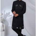 Man wearing a black Indo-Western sherwani with detailed black embroidery and beadwork.