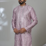 an wearing a multicolor floral printed kurta with mirror work embroidery on the neckline, paired with white trousers and black loafers, standing indoors against a neutral backdrop.