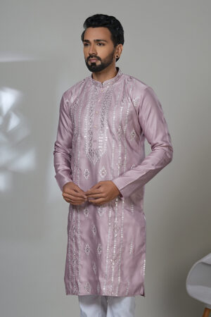 an wearing a multicolor floral printed kurta with mirror work embroidery on the neckline, paired with white trousers and black loafers, standing indoors against a neutral backdrop.