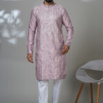 an wearing a multicolor floral printed kurta with mirror work embroidery on the neckline, paired with white trousers and black loafers, standing indoors against a neutral backdrop.