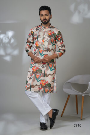 Man wearing a multicolor floral printed kurta with mirror work embroidery on the neckline, paired with white trousers and black loafers, standing indoors against a neutral backdrop.