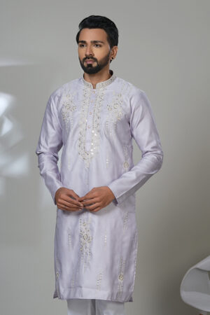 Man wearing a pastel lilac kurta with white embroidered floral and linear designs, styled with white pants—a sophisticated traditional outfit.