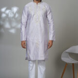 Man wearing a pastel lilac kurta with white embroidered floral and linear designs, styled with white pants—a sophisticated traditional outfit.