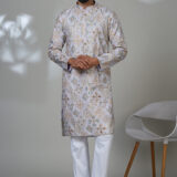 Man wearing a lilac embroidered kurta with mirror and thread work, white trousers, and brown shoes — a statement ethnic wear look.