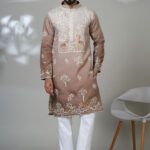 Man wearing a taupe kurta with white and copper peacock embroidery, white pants, and brown loafers — an artistic and regal ethnic outfit.
