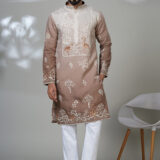 Man wearing a taupe kurta with white and copper peacock embroidery, white pants, and brown loafers — an artistic and regal ethnic outfit.