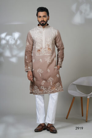 Man wearing a taupe kurta with white and copper peacock embroidery, white pants, and brown loafers — an artistic and regal ethnic outfit.
