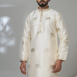 Man wearing an ivory silk kurta with gold elephant embroidery, white trousers, and brown shoes — perfect for festive or formal Indian wear.