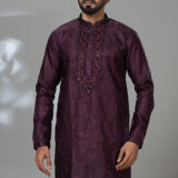 Man wearing a deep maroon embroidered kurta with white pants and black shoes, perfect for formal festive wear.