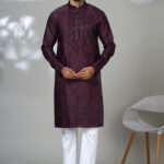 Man wearing a deep maroon embroidered kurta with white pants and black shoes, perfect for formal festive wear.