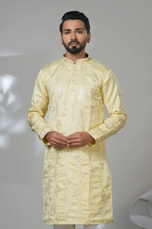 Man in a lemon-yellow kurta with geometric mirror embroidery, paired with white trousers and black shoes.