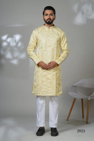 Man in a lemon-yellow kurta with geometric mirror embroidery, paired with white trousers and black shoes.