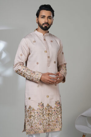 Man in a light pink kurta with intricate floral embroidery on the hem and sleeves, worn with white pants.