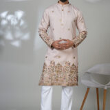 Man in a light pink kurta with intricate floral embroidery on the hem and sleeves, worn with white pants.