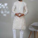 Man in an ivory kurta with mirror work and white pants, styled in a modern ethnic look.