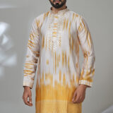 Man wearing a yellow and white ombre kurta with embroidery and white trousers, standing in a modern room with a white chair.