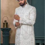 Ivory silk groom sherwani with architectural embroidery and pastel detailing