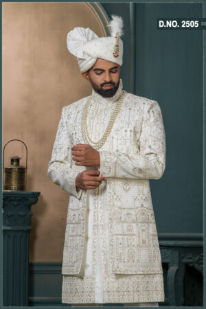 Groom in an ivory sherwani with architectural and floral embroidery, styled with layered pearl necklaces and an elegant traditional look.