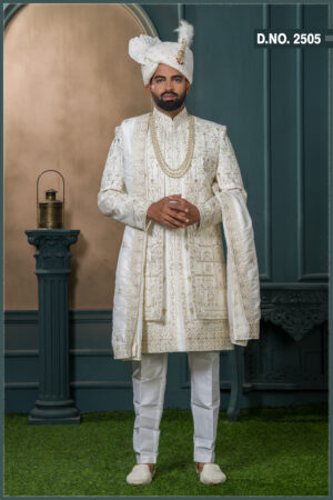 Groom in an ivory sherwani with architectural and floral embroidery, styled with layered pearl necklaces and an elegant traditional look.
