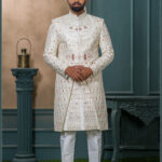 Ivory brocade sherwani with handcrafted elephant embroidery and detailed zari work for groom.