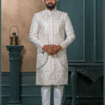 Ivory brocade sherwani with red and gold embroidery for groom wedding wear