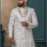 Ivory sherwani with geometric embroidery and red stone detailing for groom wedding wear