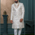 Ivory sherwani with geometric embroidery and red stone detailing for groom wedding wear