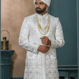 White zardozi embroidered sherwani for groom with intricate threadwork and royal turban.