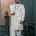 White zardozi embroidered sherwani for groom with intricate threadwork and royal turban.
