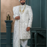 White zardozi embroidered sherwani for groom with intricate threadwork and royal turban.