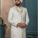 Ivory sherwani for groom with sequin and thread embroidery, paired with royal turban and pearl mala.