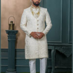 Ivory sherwani for groom with sequin and thread embroidery, paired with royal turban and pearl mala.