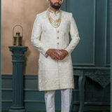 Ivory sherwani for groom with sequin and thread embroidery, paired with royal turban and pearl mala.