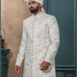 Ivory sherwani with pastel thread and zardozi embroidery, worn with traditional turban and feather adornment.