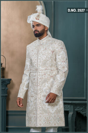 Ivory sherwani with pastel thread and zardozi embroidery, worn with traditional turban and feather adornment.
