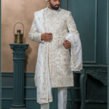 Ivory sherwani with pastel thread and zardozi embroidery, worn with traditional turban and feather adornment.