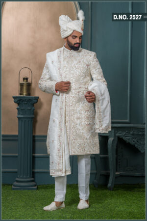 Ivory sherwani with pastel thread and zardozi embroidery, worn with traditional turban and feather adornment.