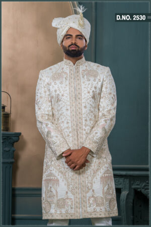 Ivory sherwani with elephant and peacock zardozi embroidery, styled with a cream turban and feather, ideal for a royal groom look.