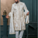 Ivory sherwani with elephant and peacock zardozi embroidery, styled with a cream turban and feather, ideal for a royal groom look.