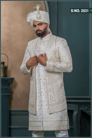 Ivory sherwani with intricate gold zardozi embroidery and turban with feather, styled for an elegant groom look.