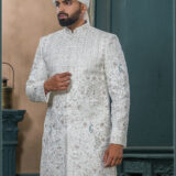 Ivory sherwani with silver and blue embroidered peacock motifs, paired with a cream turban featuring feather embellishment.