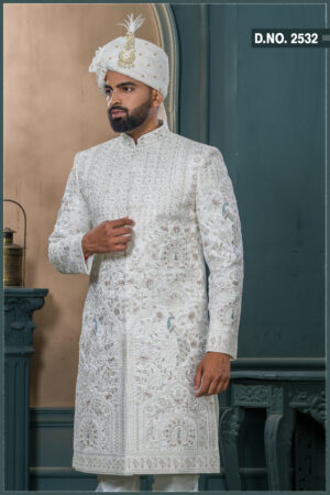 Ivory sherwani with silver and blue embroidered peacock motifs, paired with a cream turban featuring feather embellishment.