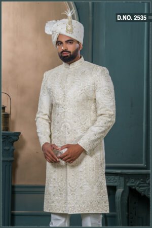 Ivory sherwani with detailed thread and zari embroidery, paired with a matching ivory turban featuring gold embellishment and feather accent.