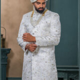 Ivory silk sherwani with golden thread and pearl embroidery, paired with an ivory turban featuring feather detailing and layered pearl mala.