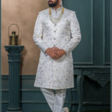 Ivory silk sherwani with golden thread and pearl embroidery, paired with an ivory turban featuring feather detailing and layered pearl mala.